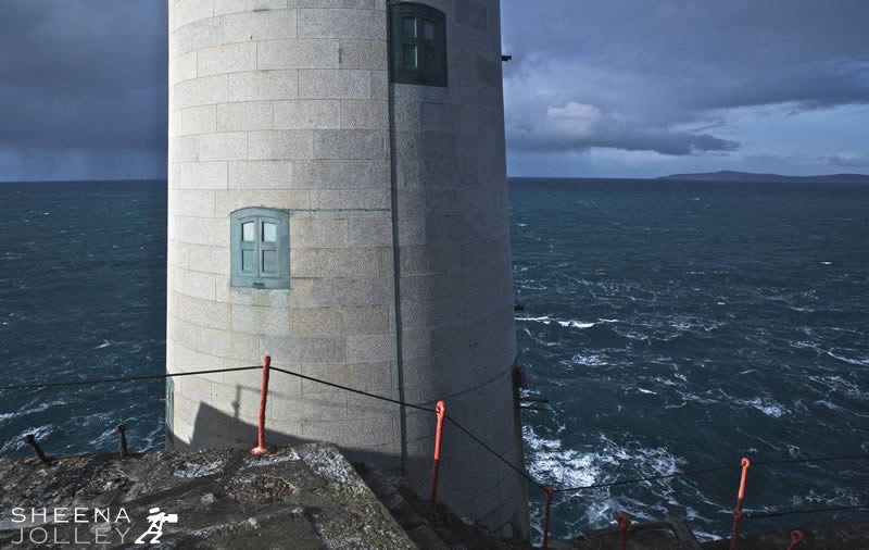 Storm on Fastnet.jpg - A close up of the structure of the fastnet lighthouse showing the blockwork. A tense moment as an approaching storm is looming turning the clouds an inky blue and whipping up the ocean waves.